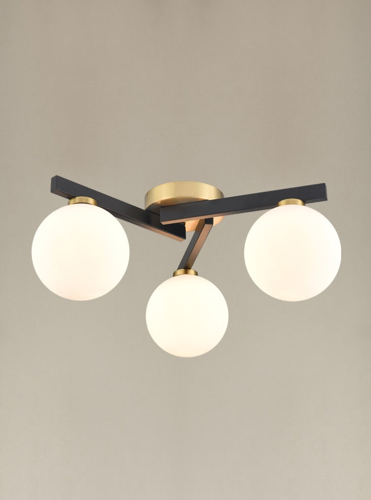 A black and gilt asymmetric light fitting. The three opaque globe lights sit on 3 black struts linked by gilt metal central rose. A really bright and contemporary pendant, adding an interesting, chic modern look to the smallest rooms