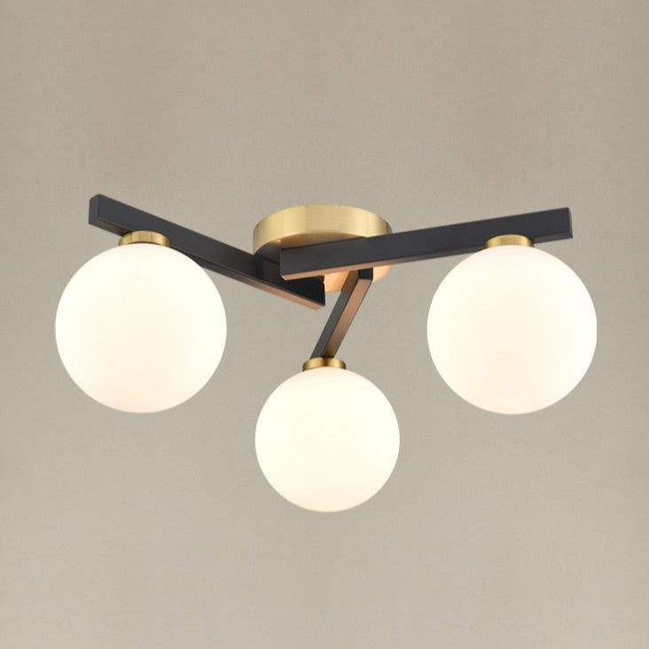 A black and gilt asymmetric light fitting. The three opaque globe lights sit on 3 black struts linked by gilt metal central rose. A really bright and contemporary pendant, adding an interesting, chic modern look to the smallest rooms