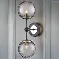 A very smart black double globe ribbed glass ball wall light with black iron and brushed nickel metal arms and circular wall plate. 
With deco tones, this contemporary wall light easily complements any interior style.  Discreet black ribbed glass globe balls mean that light can be softly diffused from the warm white G9 bulbs that can be purchased separately from our site.  
This black ribbed glass wall light seamlessly integrates into any space without over dominating. 