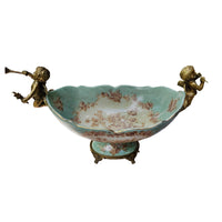 Lift your table decor with our stunning Bronze Cherub Porcelain Bowl, an heirloom piece and a masterpiece of craftsmanship and elegance. This beautiful bowl features intricate bronze cherubs adorning each end, resting delicately on tiny bronze feet. 
Designed to impress, this bowl is more than just a functional piece—it's a work of art. The sloping scalloped edge adds a touch of sophistication, making it perfect for displaying fresh blooms, or even a bountiful arrangement of fruit. Measuring 32 cm in