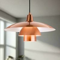 A brushed copper metal tiered pendant light with a black cable, hanging in a room setting.