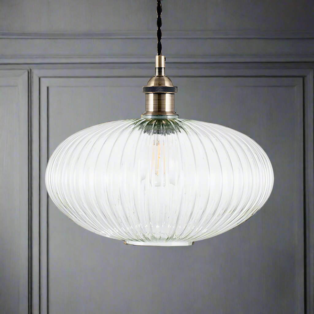 Ribbed glass and brass metal pendant light in an oval, pumpkin shape.  The ribbed glass acts to diffuse the light and gives an vintage feel to the space.  Great over a kitchen island or anywhere in the kitchen.