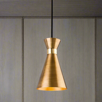 A conical metal pendant light in a brass color, hanging from a ceiling with a wooden background.