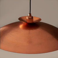 Modern pendant featuring a hammering copper metalwork finish with a black flex.  This copper disc pendant light is a striking, contemporary lighting fixture that combines sleek design with industrial charm. Its wide shape allows the light to spread evenly across any room. It is a very stylist and ideal for living rooms, bedrooms and kitchens