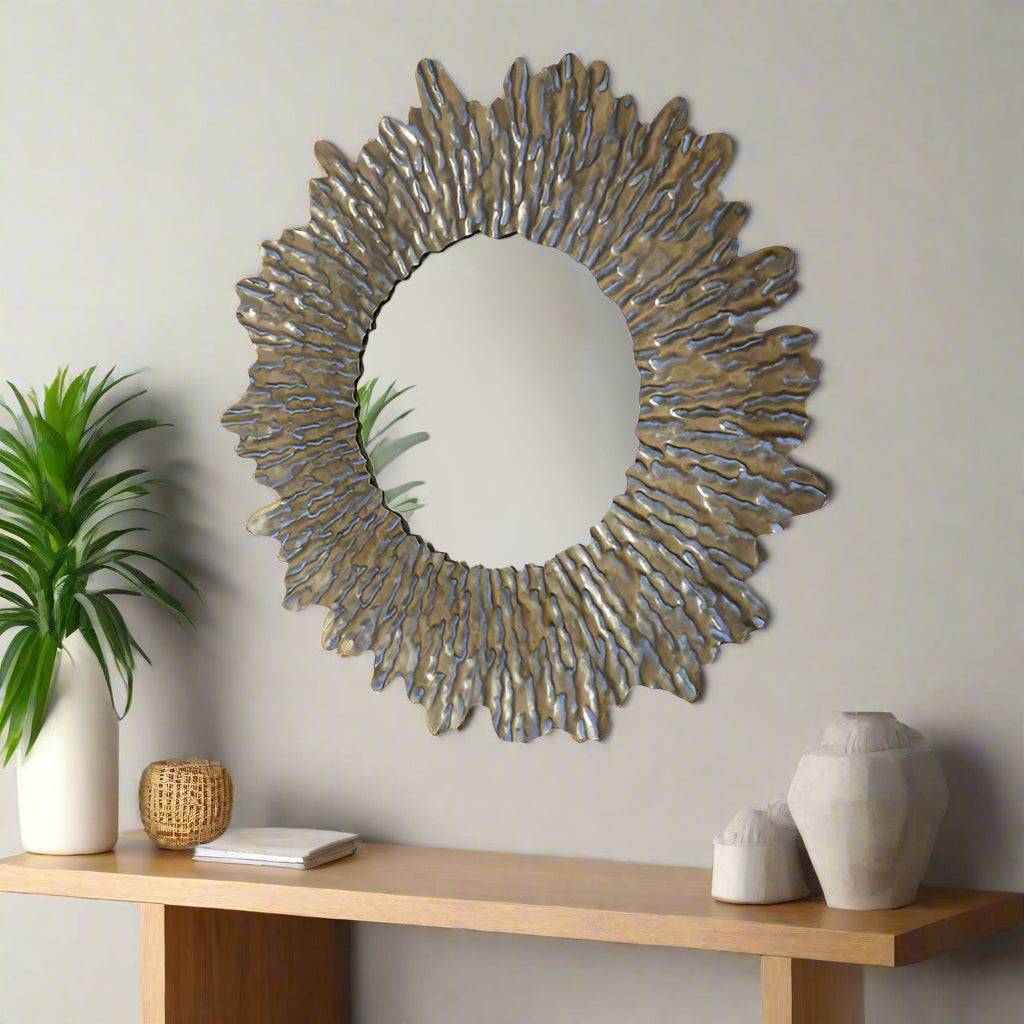 Round sun wall mirror with a distressed gold textured frame. The shape adds a touch of movement to its design. The distressed gold finish gives an antique feel