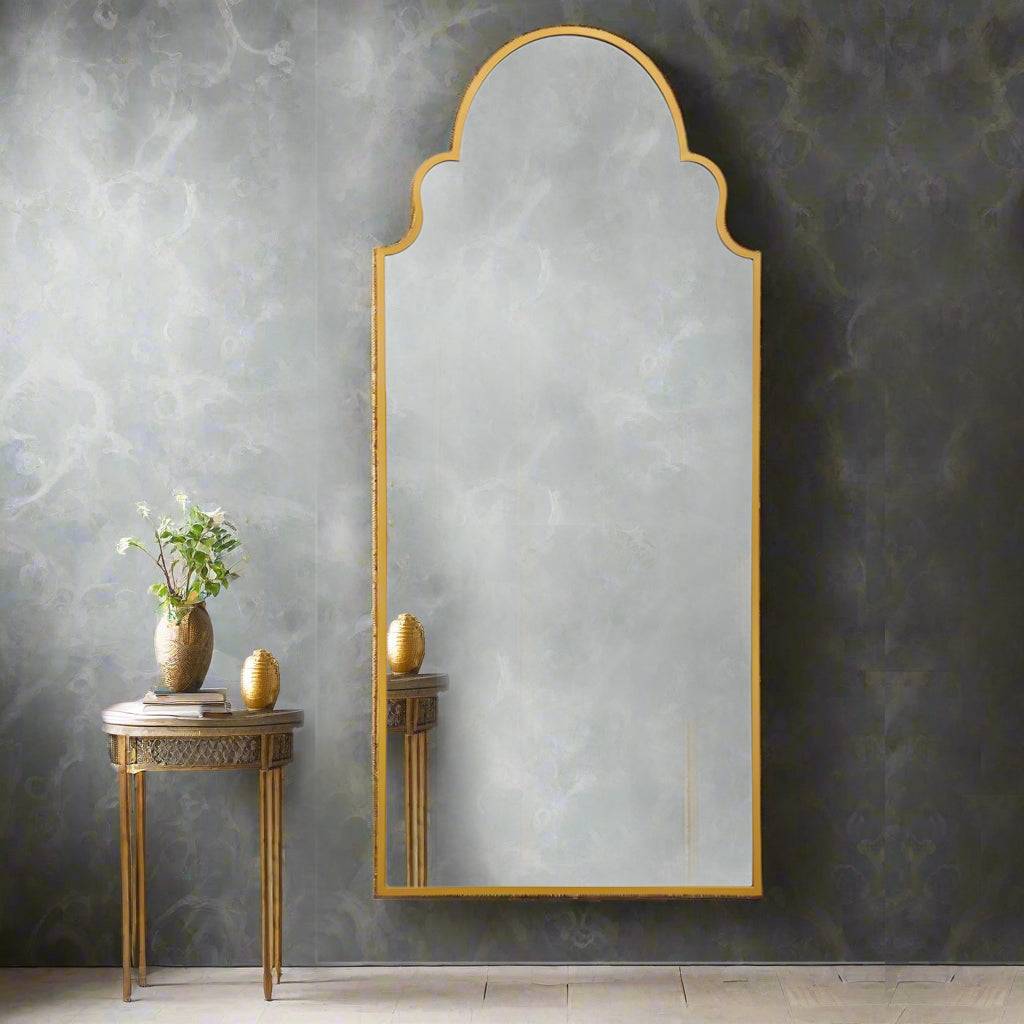 This is an extra-large mirror with a gold frame and an elegant arched shape. The top of the mirror features a decorative scalloped design, giving it a sophisticated and classic feel. The frame is slim and refined, enhancing the mirror’s stylish and timeless aesthetic. This type of mirror would work beautifully in various spaces, such as entryways, bedrooms, or living rooms, adding a touch of luxury and making the room feel more open and bright.
