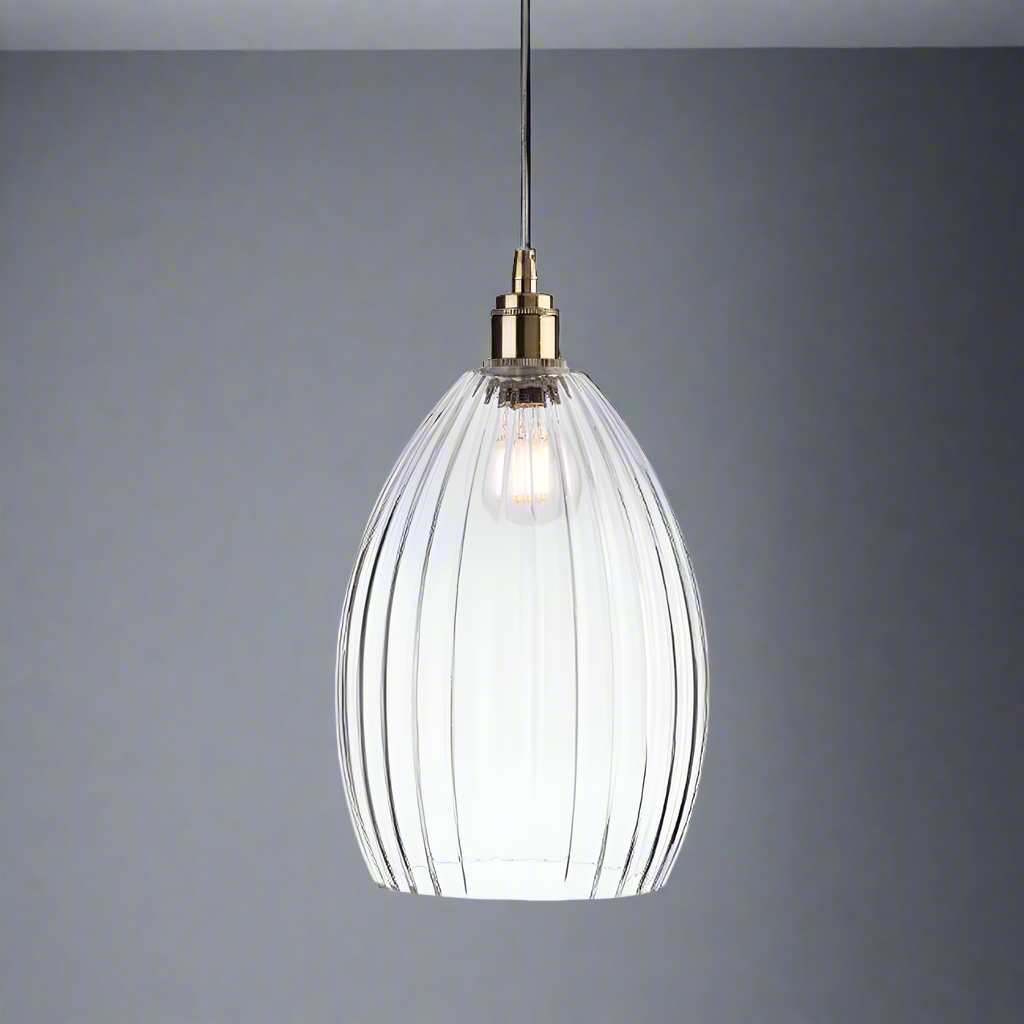 A long ribbed glass and antique brass metal pendant light. This long pendant can take a large led bulb allowing for a lot of light and a warm muted glow from the ribbed glass, Perfect kitchen island light, or in a bedroom. Great in a hall will illuminate and add a glow to any room.