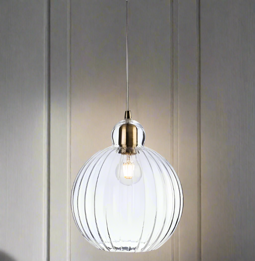 A round ribbed glass pendant light with antique brass metalwork.  A pretty, round ribbed shape which would work well in a kitchen, cloakroom or even in a bedroom. The ribbed glass subtly diffuses the light and reduce glare.