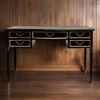 A black metal five drawer desk or console table in the industrial style with brushed gilt handles to the drawers and gilt accents to the front of the table.  A real industrial feel that would not look out of place in a classic or country style home.  Five really useful storage drawers if used in a study or a library as your desk.