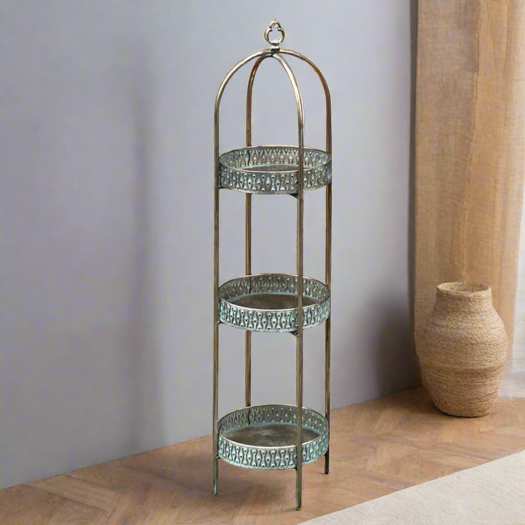 A unique and very pretty shelf unit with pierced metal detailing around the shelves which can be lifted out and also used as trays.  Finished in a rustic antique gold colour, this metal unit has three shelves encased in an outer frame that can fold flat.  
This is useful storage with a Moroccan vibe for small spaces that will quickly declutter your home.  Can be used in every room and looks particularly glamorous in bathrooms and conservatories. 