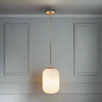 Long white glass pendant with a soft gold fitting and ceiling rose.    Opaque glass has the benefit of offering a warm diffused glow in a room, perfect in a bedroom, hall or living room where warm, welcoming lighting is a must. The other benefit of opaque pendants is that they hide the bulbs.
H: 150 cm W: 15 cm