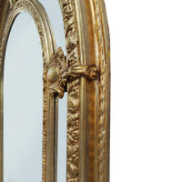 Extremely ornate arched gold mirror with beveled panels.  This statement mirror would look amazing in a hallway, just opening up the space and adding a luxurious air to your entryway. In a living room to flash out light and give the illusion of extra space.  Stunning rococo revival style with swags and medallions to the crown and heavily ornamented frame. The gilding is a beautifully opulent gilt leaf giving the frame an opulent lustre.  
There is no room in the house that would not ben