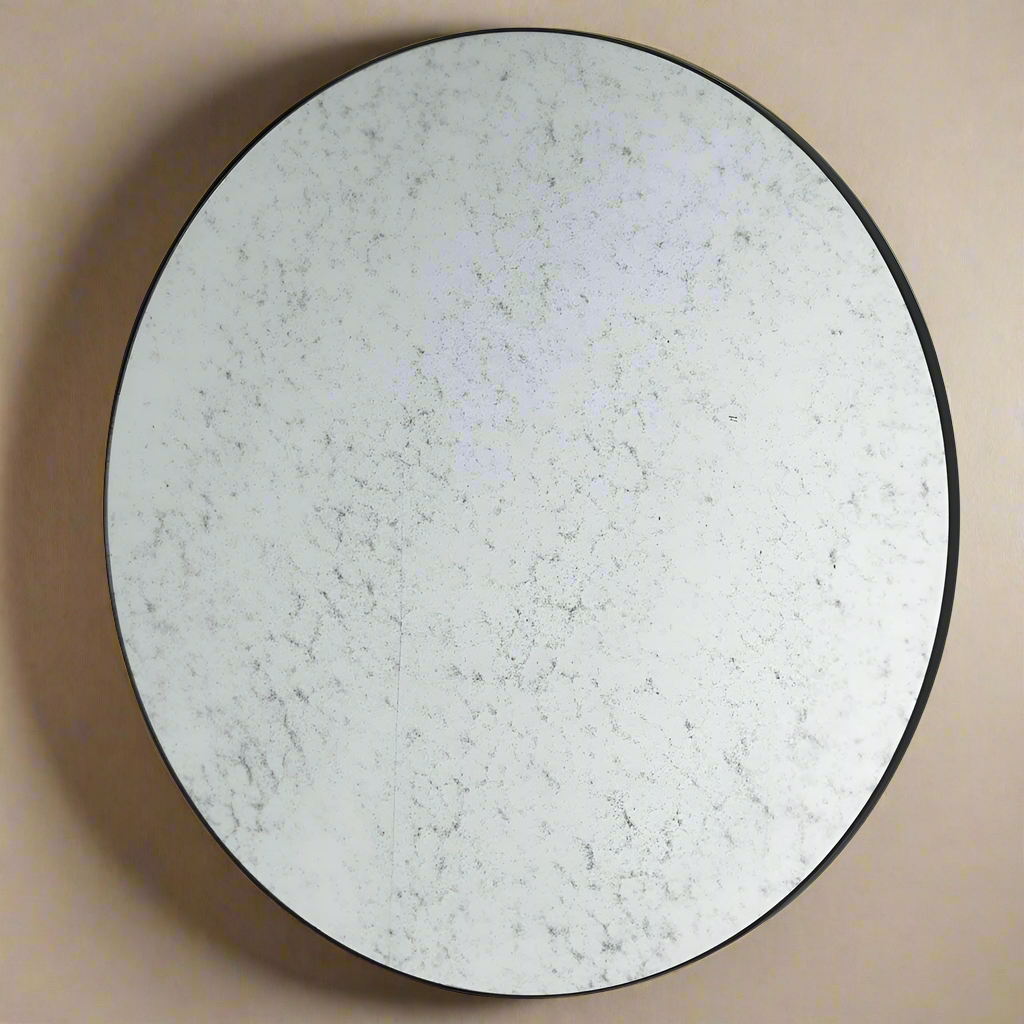 Circular aged black rimmed mirror.  A simple iron frame with aged Venetian glass makes this a feature mirror for spaces that need to be lit up without a domineering reflection.A perfect kitchen, hall or even outdoor mirror.