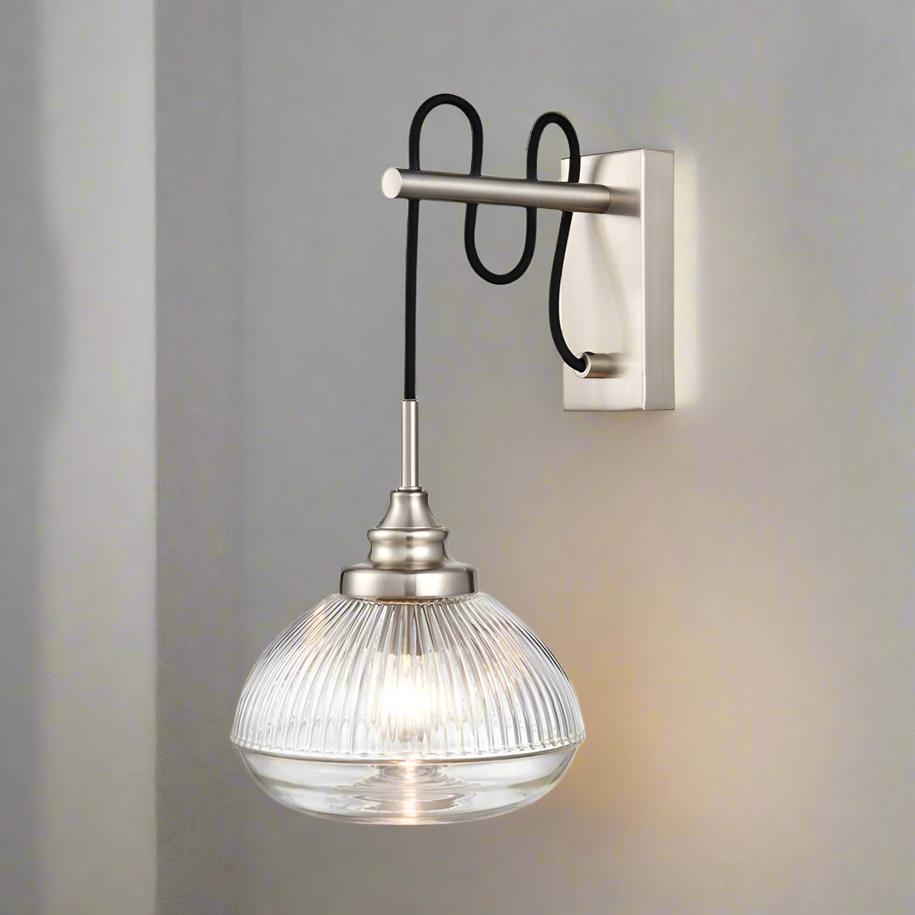 A satin nickel and ribbed clear glass wall light mounted on a wall, with visible bulb (not included).