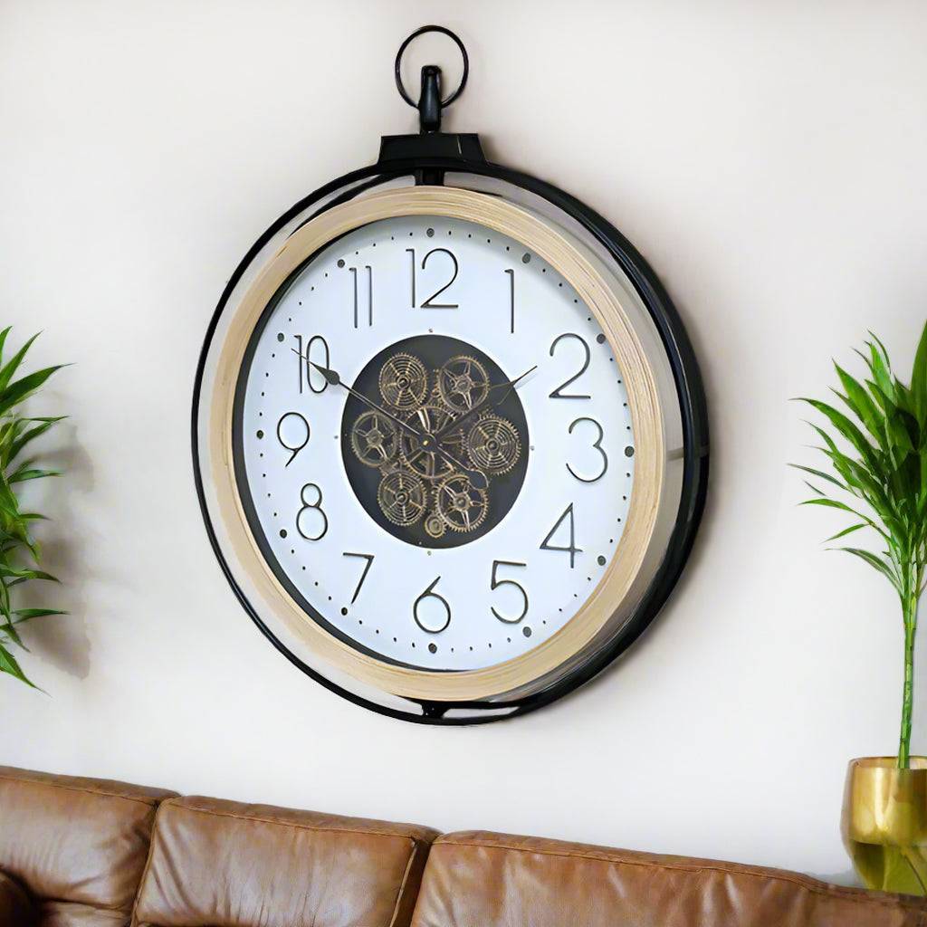 A large moving cog clock with white enameled face and pale wooden surround. The entire cog clock is encased in a iron frame. A statement clock which will enhance any wall