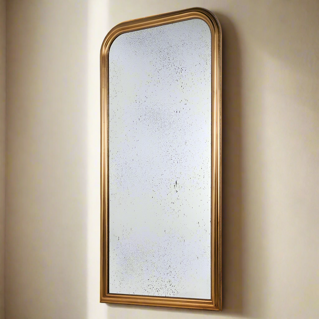 Large arched aged glass mirror with a gilt beaded frame, measuring 183 cm in height, leaning against a beige wall. Perfect for luxury home decor.