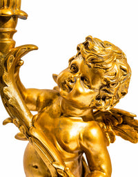 Gold cherub table light, perfectly formed cherubim hand outstretched holding a lamp.  The lamp looks best with the addition of a filament bulb to add a glow.  The lamp has a rococo decorative style working well in a luxurious bedroom, baroque styled living room - anywhere you need a touch of glamour.   So decorative but also perfectly functional. 