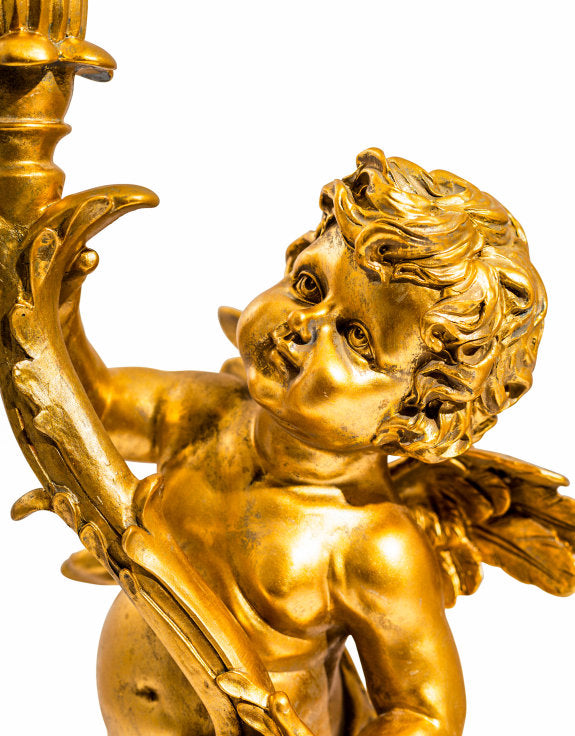 Gold cherub table light, perfectly formed cherubim hand outstretched holding a lamp.  The lamp looks best with the addition of a filament bulb to add a glow.  The lamp has a rococo decorative style working well in a luxurious bedroom, baroque styled living room - anywhere you need a touch of glamour.   So decorative but also perfectly functional. 