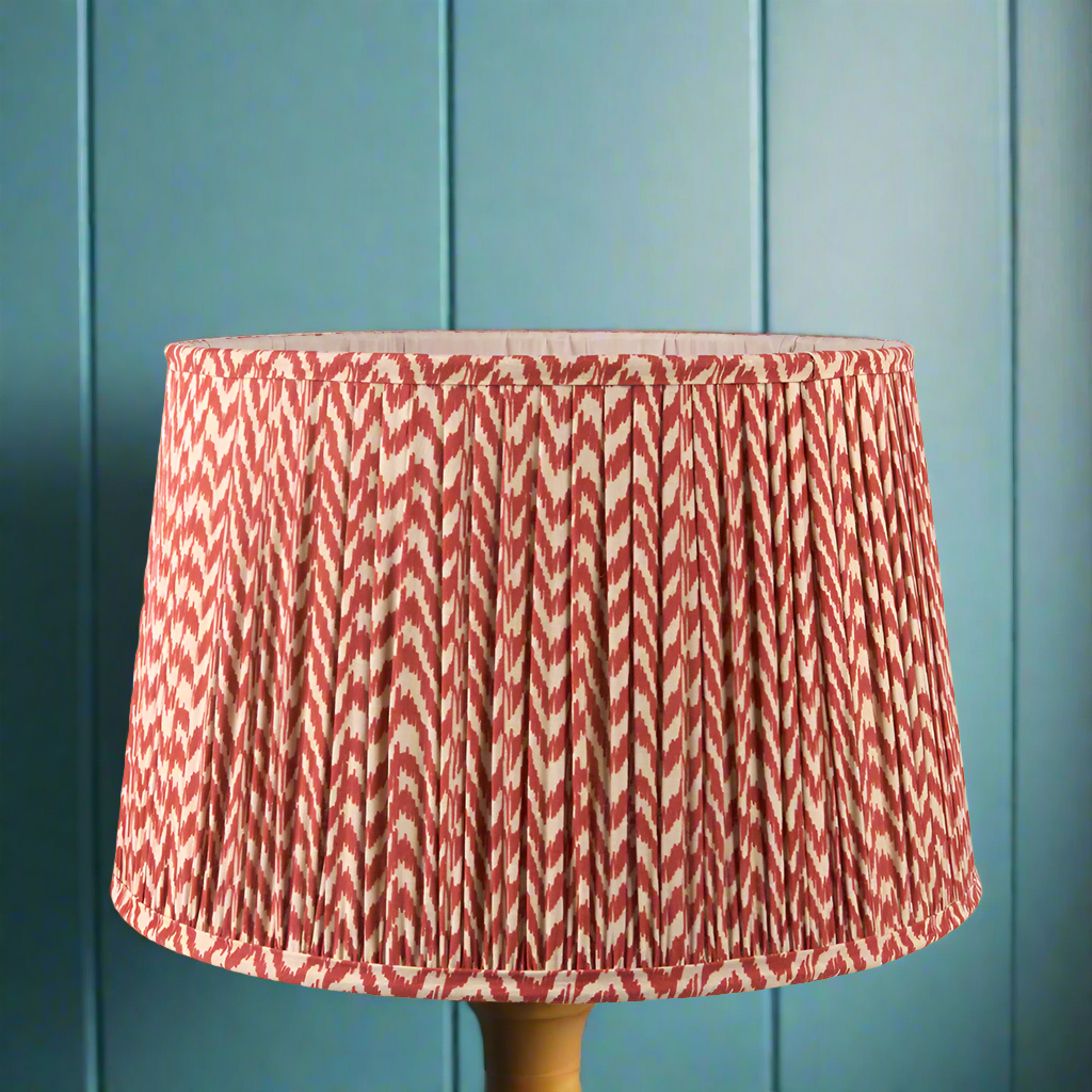 Pleated chevron patterned lamp shade in red and white, displayed on a blue background.