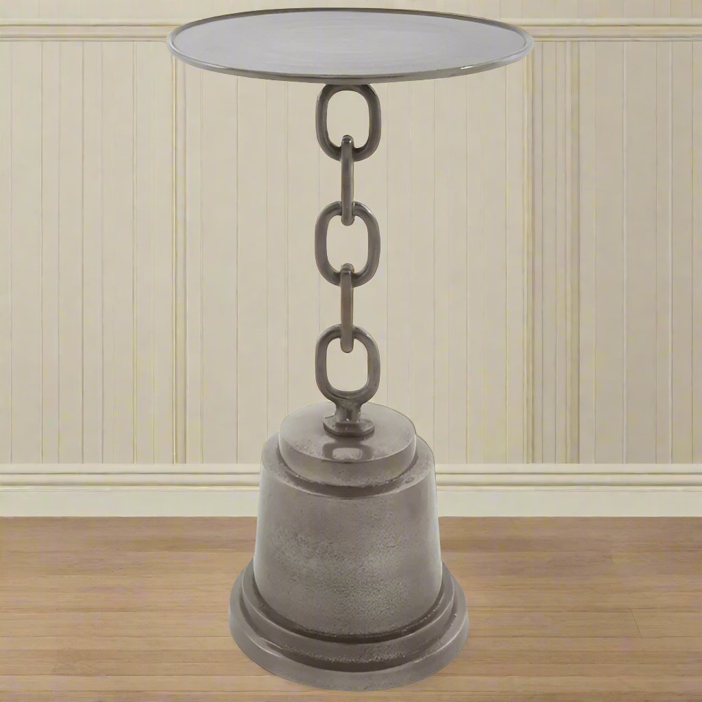 A tall side table with a round top and a chain stand connecting to a pedestal base, made of aluminium, displayed against a indoor background.