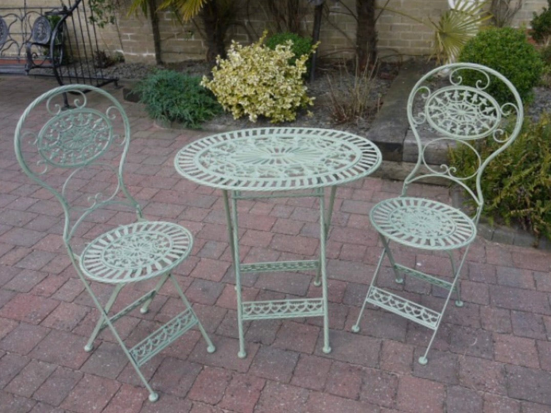 Green iron garden furniture table and two chairs, fully folding for easy winter storage. The oval table is a neat size and shape and a very pretty green colour.  The three pieces are made from powder coated iron, to allow for weather resistance and durability.  The table is a classic openwork lattice pattern, matched by the pattern on the chairs. The set is the perfect size for a smaller garden and perfect for a patio or balcony. The ideal size for two people to enjoy a drink outdoors.