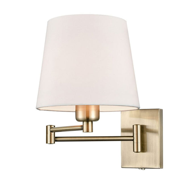 A modern wall-mounted sconce with a tapered off-white fabric shade and a brushed brass-finish metal arm and wall plate,