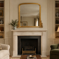 An ornate gold-framed overmantle mirror above a fireplace in a classic living room 