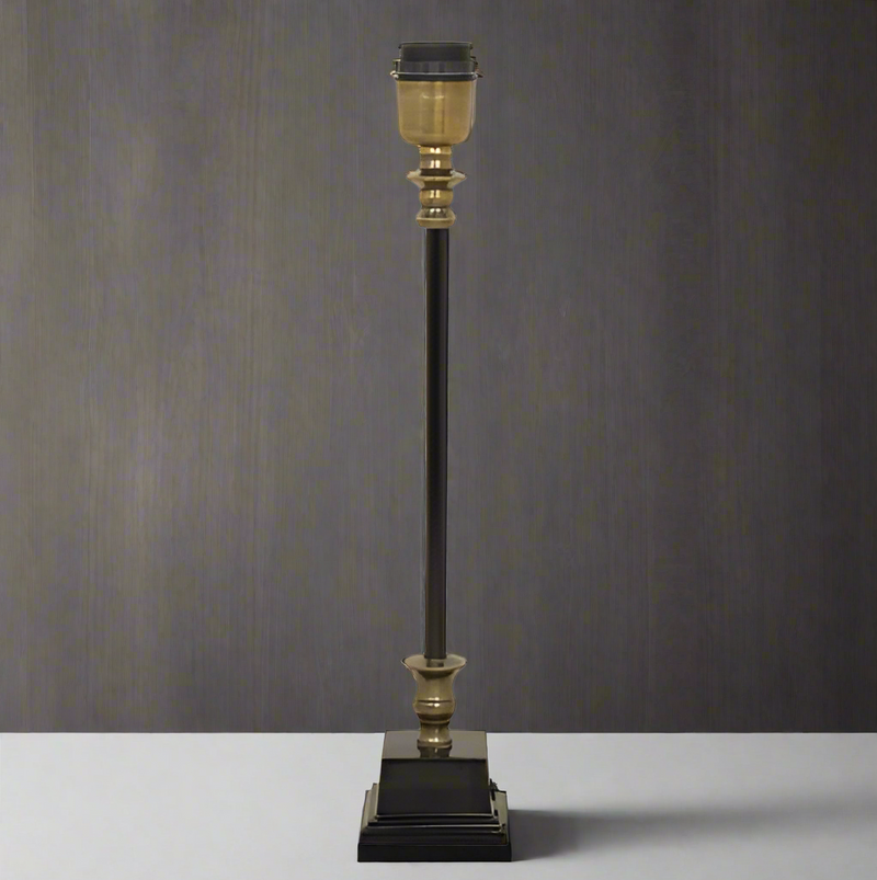 A classic, column lamp base in antique bronze with brass accents to the base. This is sold as a base only, giving you the opportunity to add your own shade.&nbsp; A perfect bedside table lamp size, or on a console table, these lamps can be dressed up or down with coloured shades to fit any interior.