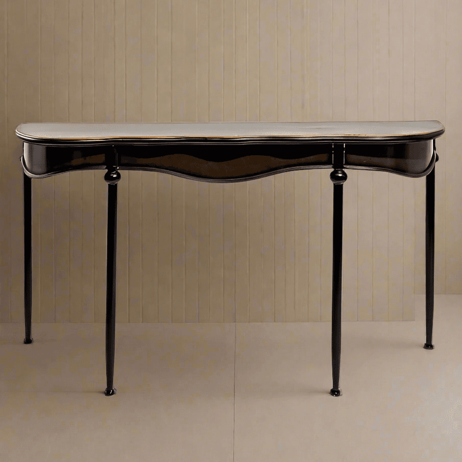 Medium size curved metal console table with pale gilt accents to the rim or the top. The curved metal frame of this black table adds a soft sculptural element.