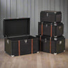 Set of four black trunks in varying sizes.&nbsp; The three larger trunks are banded with wooden straps and nickel studs. Trunks are such a useful item of furniture, perfect for storage but can also be used as a side table in a living room, bedroom study or for storing shoes in a hall. The black hessian covering will work in so many interiors