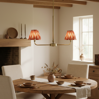 A refined ceiling light featuring an brass frame with two curved arms, each supporting a classic tapered fabric clip shade. 