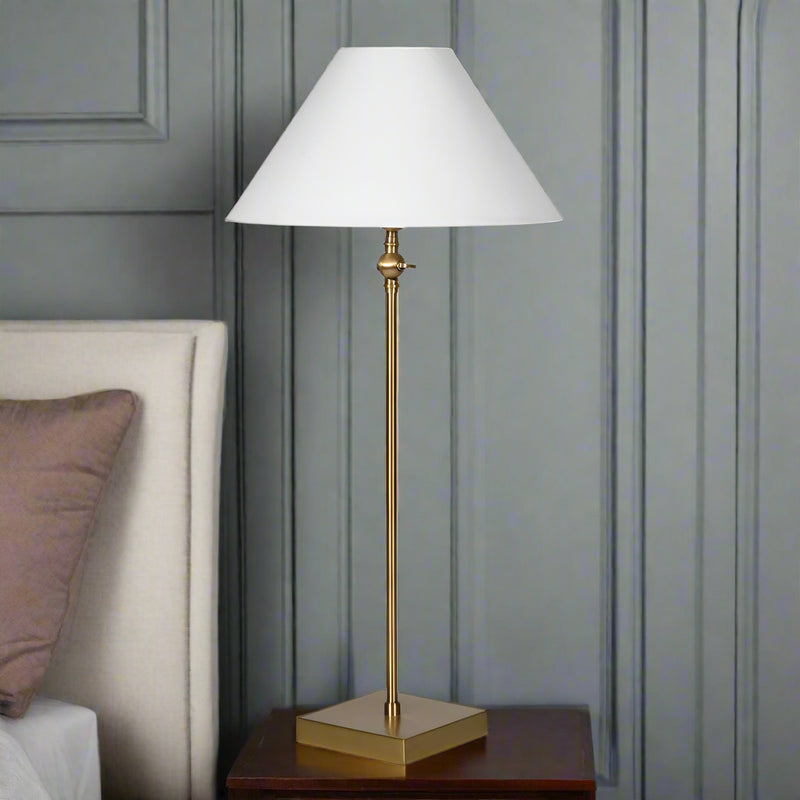 Bring timeless elegance to your bedroom with this bedside table lamp, designed to add both style and functionality to your nightstand. Featuring a slim antique brass base and a crisp white fabric lampshade, this lamp creates a warm, soft glow—perfect for reading before bed or creating a cozy bedroom atmosphere.

Its tall, space-saving design makes it an ideal nightstand lamp for small or large bedside tables, while the neutral color palette complements both modern and traditional bedroom décor. Whether you 