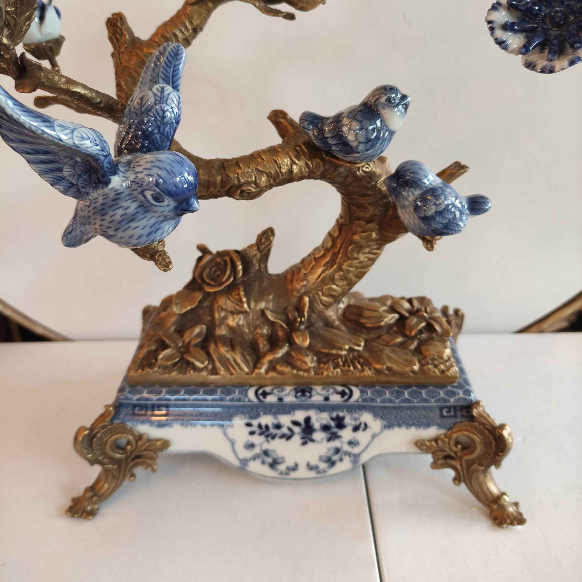Blue and white porcelain bird figurines on ornate bronze tree branch