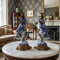 Pair of decorative blue parrot statues on a marble table in an elegant room.