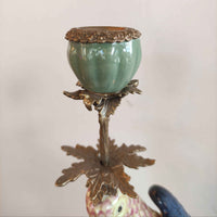 A pair of a colourful porcelain parrot candle holders with gilt bronze detailing. Crafted to exceptional quality, they add luxurious warmth and timeless charm to refined interiors