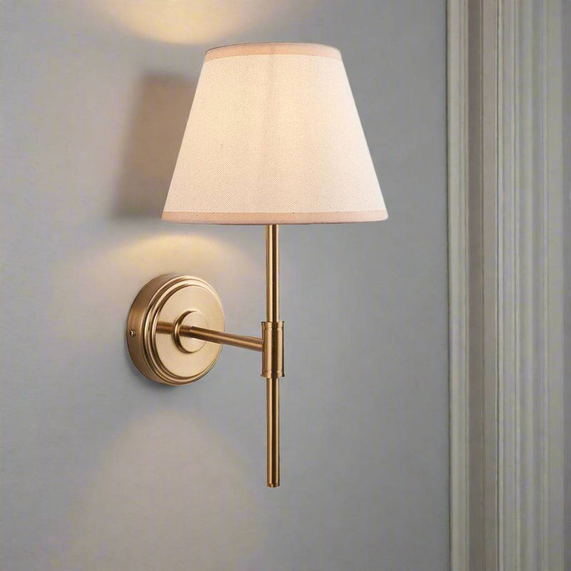 Very simple, classic shaded wall light in brushed aged brass. The neutral shade is a perfect addition, totally classic. This wall light is a great bedside lamp, situated on the wall