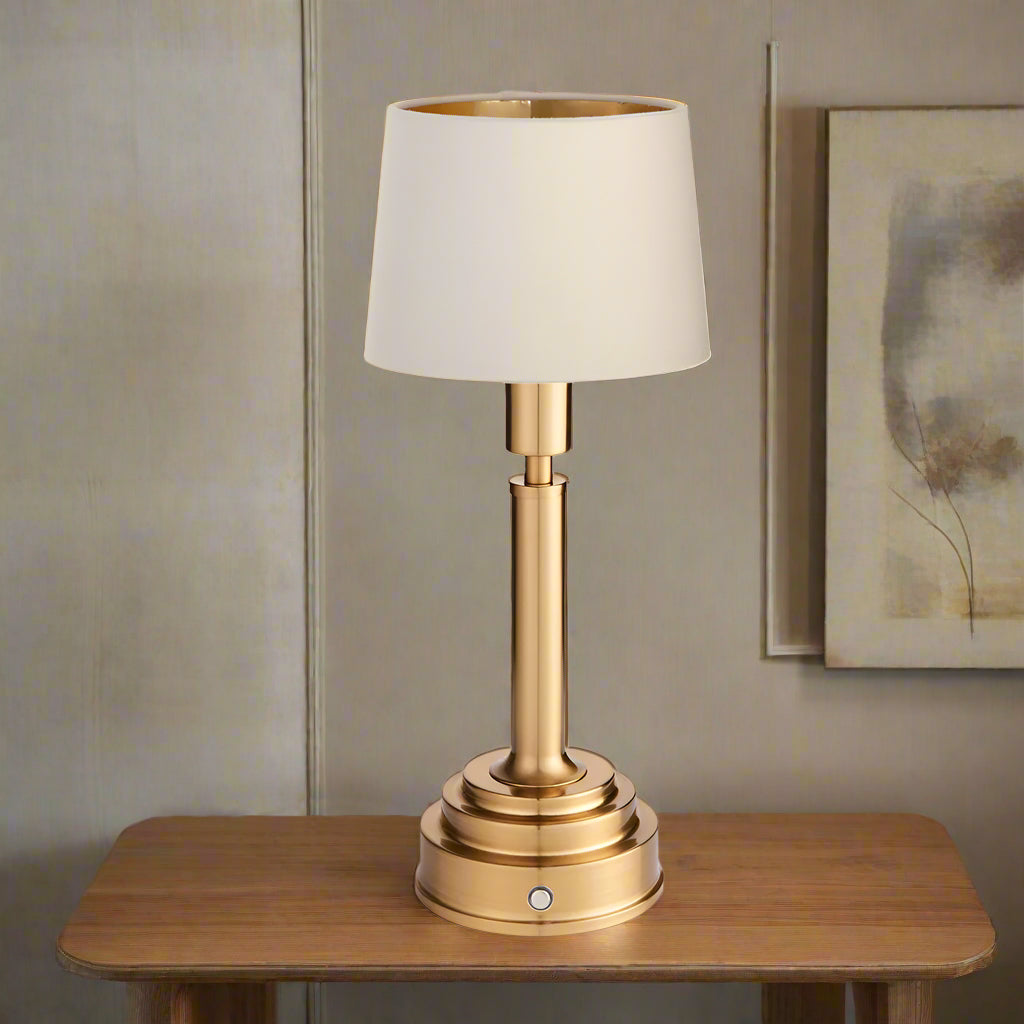 Brushed gold, rechargeable table lamp with a USB port.&nbsp; This portable, rechargeable 3 stage touch dimmer table lamp allows you to set your desired level of light.
They include a USB cable and an integrated warm white LED bulb.
These lamps are so convenient, can be placed wherever needed, no wires or plugs. Perfect for dining tables, desks or bedrooms. Can even be used outdoors making this a totally versatile lighting solution for your home.
Combine them with a inner gold clip shade in three different c