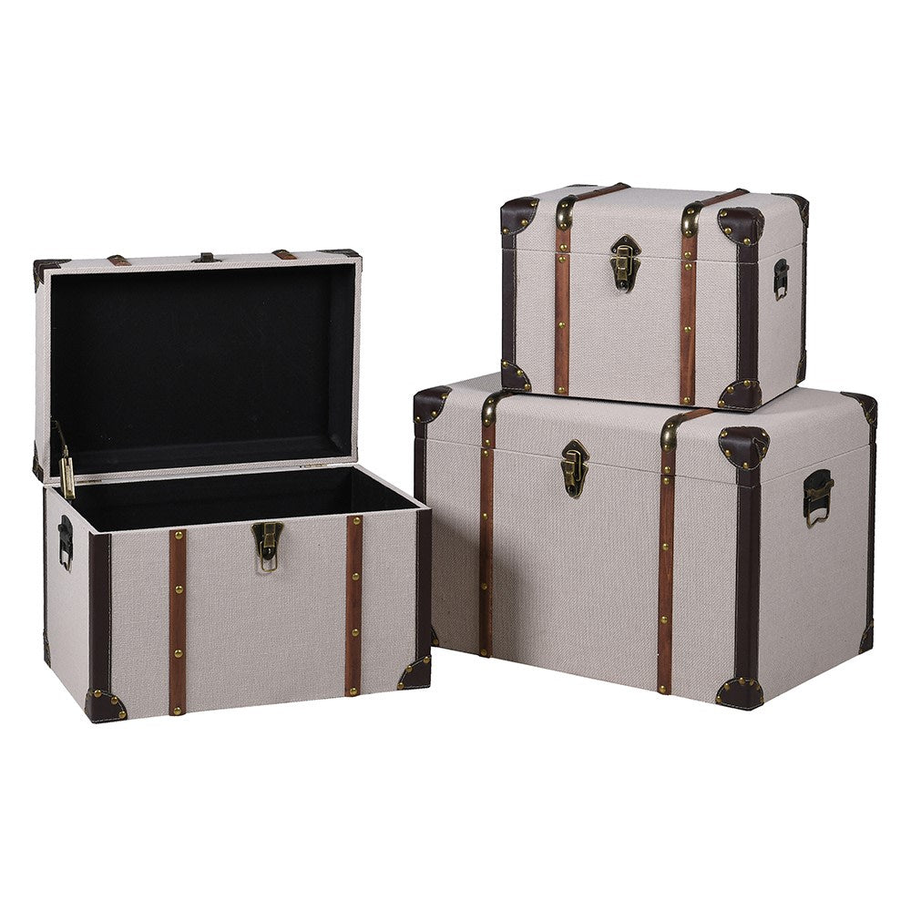 Set of 3 trunks in a light coloured fabric finish, with brass studded wooden strapping, nickel lock and nickel reinforced corners. They offer beautiful storage in a bedroom or dressing room