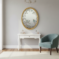 A decorative gilt framed oval wall mirror painted in the 'Victorian' style with floral motifs. A light-enhancing reflective glass surface. 