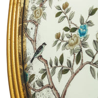 A decorative gilt framed oval wall mirror painted in the 'Victorian' style with floral motifs. 