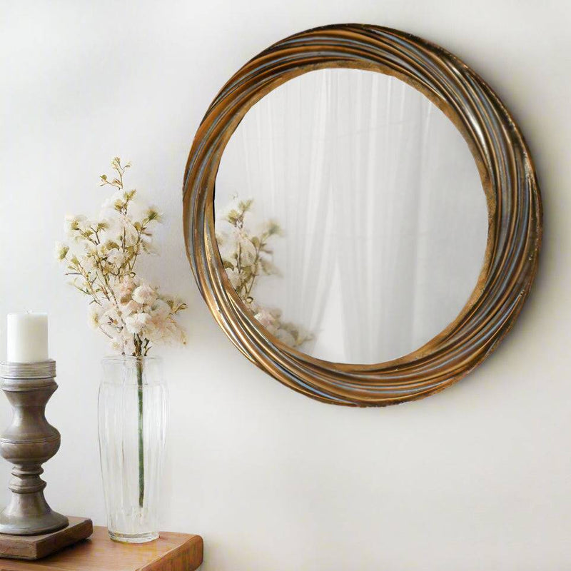A round wall mirror with a distressed gold, deeply textured frame. The swirling pattern of the frame adds a touch of elegance and movement to its design. The distressed gold finish gives a warm, antique feel. The design and finish would look especially great in hallways, living rooms, bedrooms or bathrooms - any room with a light touch of elegant spark, rich textures, and vintage-inspired décor.


