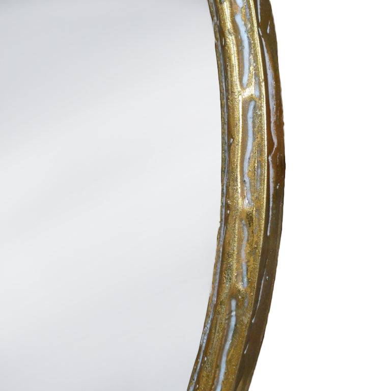 A round wall mirror with a distressed gold metal frame. The textured frame gives a vintage and rustic feel. The mirror itself is smooth and clear, providing a clean reflection. The combination of the aged gold finish and the simple, round shape creates a timeless, elegant look, making it suitable for various interior designs, from contemporary to more traditional spaces. This mirror suits any room and will add light, from every direction to any room.