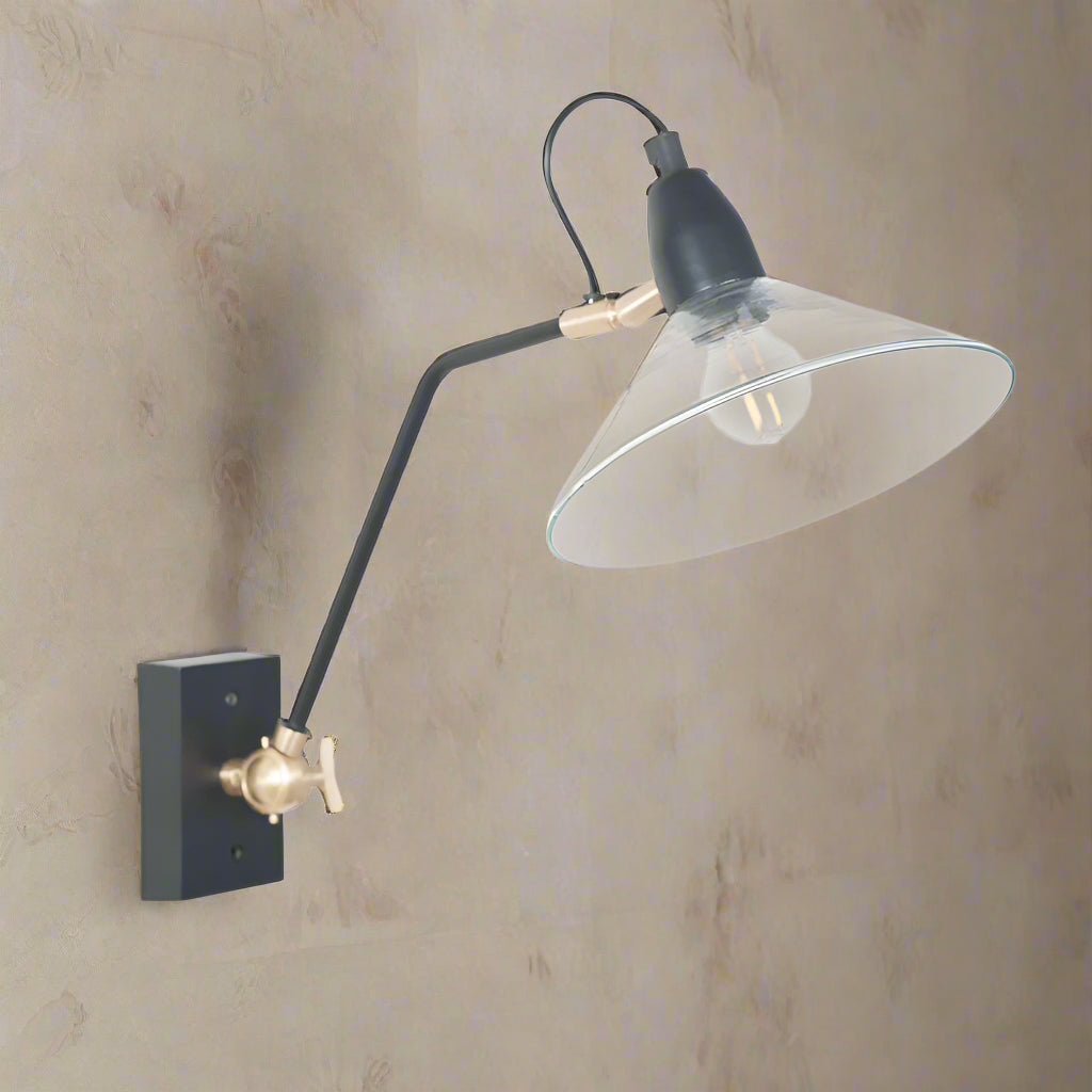 Glass and black metal long armed wall light with gilt accents to the arm. Open glass shade. An industrial style lamp,the arm of which can be adjusted from a screw on the base.&nbsp;