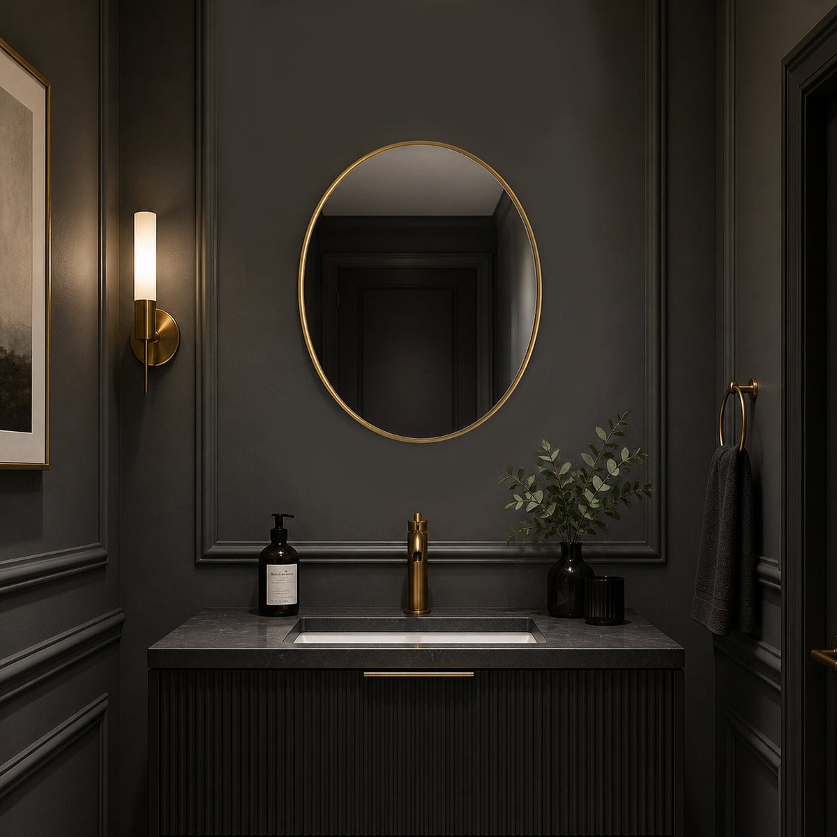 Oval gilt framed mirror in a dark grey painted cloakroom with sink and wall lighting.