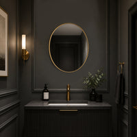 Oval gilt framed mirror in a dark grey painted cloakroom with sink and wall lighting.