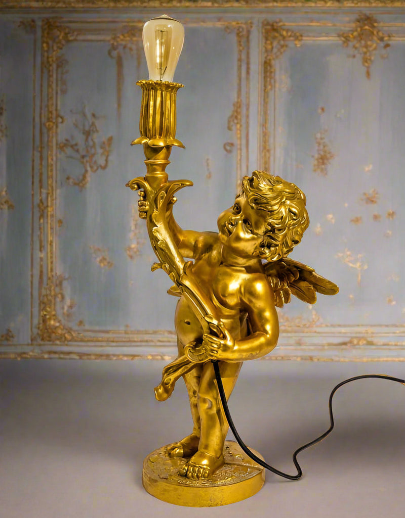 Gold cherub table light, perfectly formed cherubim hand outstretched holding a lamp.&nbsp; The lamp looks best with the addition of a filament bulb to add a glow.&nbsp; The lamp has a rococo decorative style working well in a luxurious bedroom, baroque styled living room - anywhere you need a touch of glamour.&nbsp; &nbsp;So decorative but also perfectly functional.&nbsp;