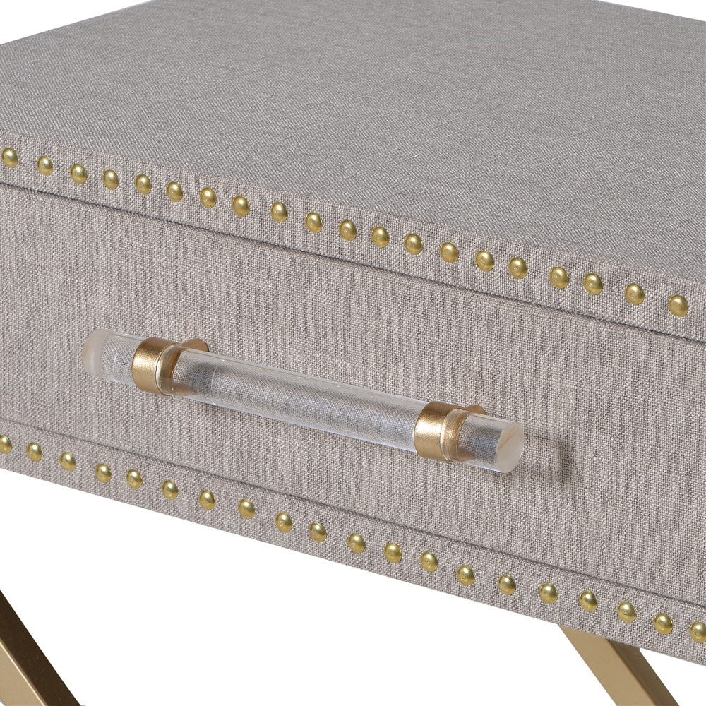 Linen drawer bedside table on brushed brass gilt crossed legs.&nbsp; A simple, easy bedside that will hold a bedside lamp and has a useful drawer for necessities. The perspex handle and brass studding around the drawer adds a luxurious touch to this contemporary piece.&nbsp;