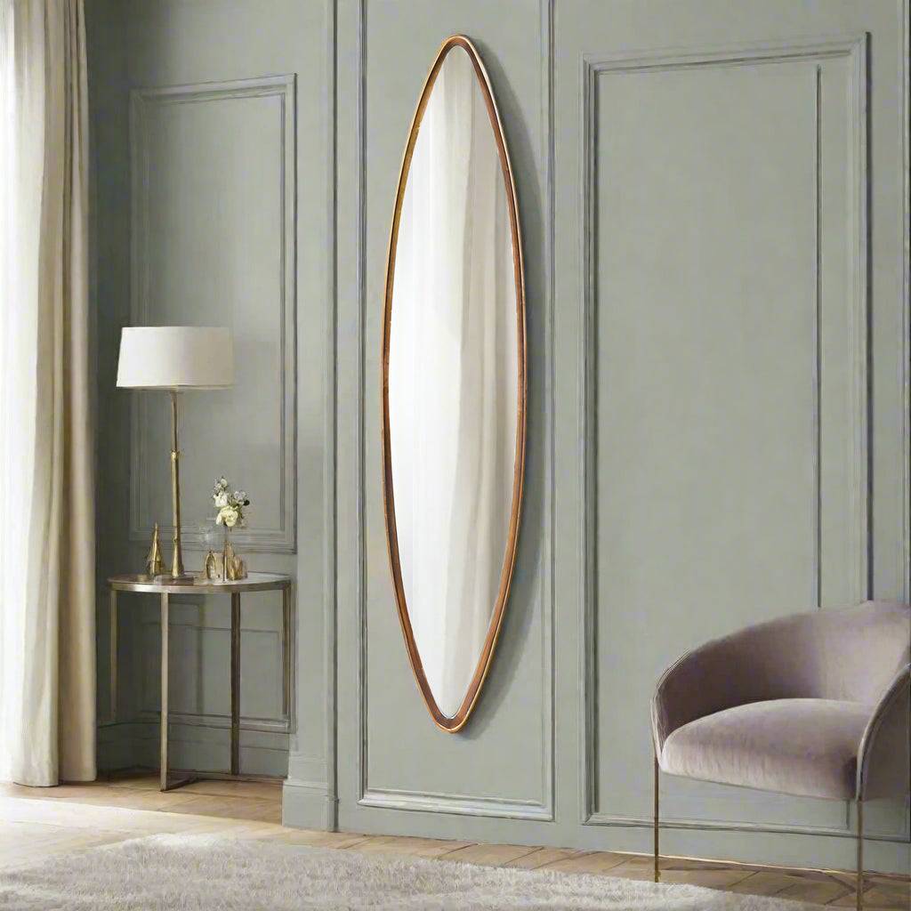 A very tall and narrow oval gilt framed mirror, perfect for those awkward areas that need light, in a bedroom