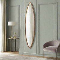 A very tall and narrow oval gilt framed mirror, perfect for those awkward areas that need light, in a bedroom
