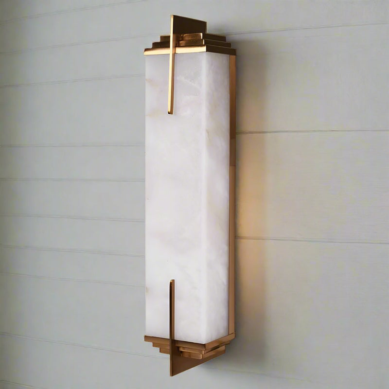 Art Deco style marble wall light.&nbsp; A typical art deco, odeon style wall light with stepped antique brass decoration to the top and base. The marble encased in a geometric styled antique brass metal. Streamlined finish to add a subtle glow to any wall.&nbsp;&nbsp; In a living room or bedroom these lights will give an opulent feel.